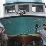 Two Pacific Star Seafoods employees work to stabilize a commercial drift fishing boat at the company's Kenai wharf.