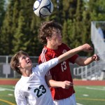 Kenai Central freshman Damien Redder (13) heads the ball with Service sophomore Dorian Cornichuck in Friday's state soccer semifinal contest at Service High School.