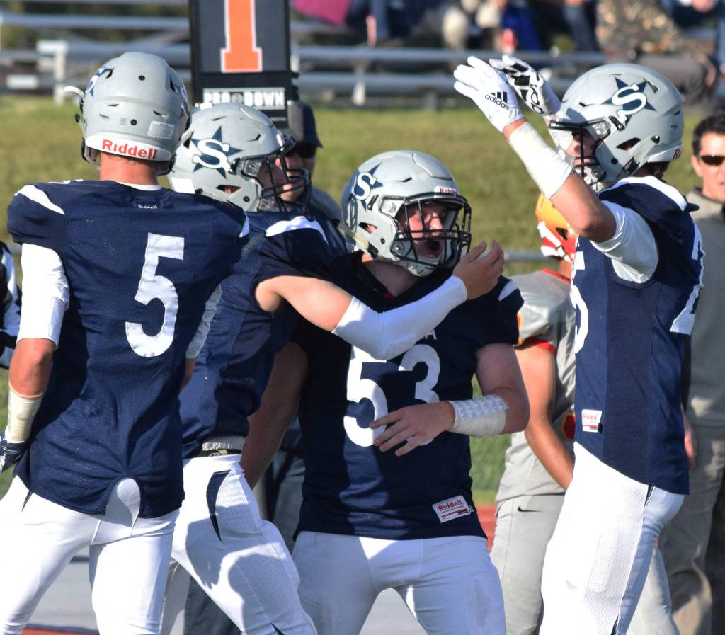 Soldotnas Jersey Truesdell hugs teammate Brennan Werner (53) along with Zach Hanson and Hudson Metcalf (5) Friday against West Valley at Justin Maile Field in Soldotna. (Photo by Joey Klecka/Peninsula Clarion)