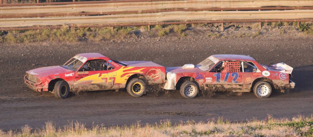 Race leader Sean Endsley (1/2) rear ends the lapped car of Mady Stichal in the A-Stock feature race Friday night at Twin City Raceway in Kenai. (Photo by Joey Klecka/Peninsula Clarion)