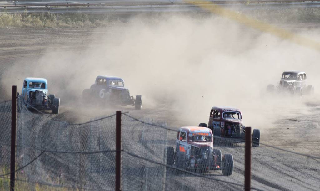 The field of Legends cars slide through a dusty turn Friday night at Twin City Raceway in Kenai. (Photo by Joey Klecka/Peninsula Clarion)
