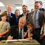 In a photo provided by the office of the governor, Gov. Bill Walker signs Senate Bill 63, a statewide public smoking ban, on Tuesday, July 17, 2018, at the Lucky Wishbone restaurant in Anchorage. The law goes into effect on Oct. 1. Standing at right is Sen. Peter Micciche, R-Soldotna, the legislative sponsor of the bill. On Walkers lap is Stella Micciche, one of Micciches daughters. Also visible, from right to left behind Walker are Dr. Jay Butler, Alaskas chief medical officer; Rep. Geran Tarr, D-Anchorage; Rep. Jason Grenn, I-Anchorage; Micciche; Rep. Chris Birch, R-Anchorage; and the smile of Emily Nenon of the American Cancer Society. (Courtesy photo)