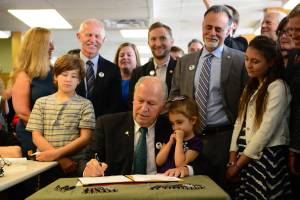 In a photo provided by the office of the governor, Gov. Bill Walker signs Senate Bill 63, a statewide public smoking ban, on Tuesday, July 17, 2018, at the Lucky Wishbone restaurant in Anchorage. The law goes into effect on Oct. 1. Standing at right is Sen. Peter Micciche, R-Soldotna, the legislative sponsor of the bill. On Walkers lap is Stella Micciche, one of Micciches daughters. Also visible, from right to left behind Walker are Dr. Jay Butler, Alaskas chief medical officer; Rep. Geran Tarr, D-Anchorage; Rep. Jason Grenn, I-Anchorage; Micciche; Rep. Chris Birch, R-Anchorage; and the smile of Emily Nenon of the American Cancer Society. (Courtesy photo)