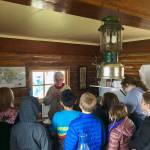 Marge Mullen shows a group of third graders around the Howard Lee Homestead, which was used as the citys first post office when she first homesteaded in Soldotna, on Wednesday, Oct. 17, 2018, in Soldotna, AK. (Photo by Victoria Petersen/Peninsula Clarion)