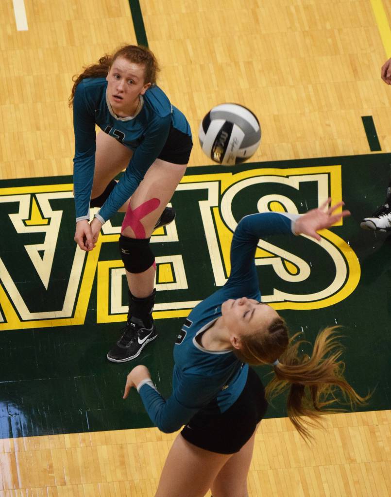 Nikiskis Kaycee Bostic (top) watches as teammate Lillian Carstens winds up for a shot Friday afternoon against Grace Christian at the Class 4A state volleyball tournament at the Alaska Airlines Center. (Photo by Joey Klecka/Peninsula Clarion)