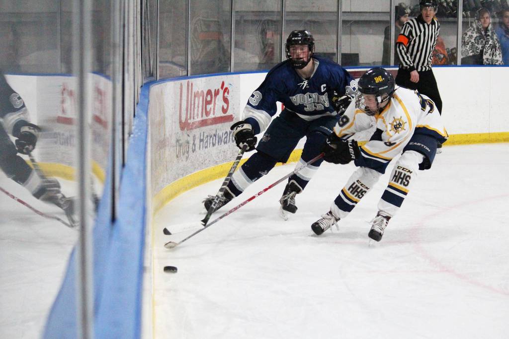 Freshman forward Casey Otis scoops the puck away from Eagle Rivers Logan Dudinsky during a game Thursday, Nov. 29, 2018 at the Kevin Bell Arena in Homer, Alaska. The Mariners fell to the Wolves 8-0. (Photo by Megan Pacer/Homer News)