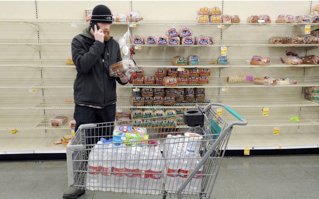 Anchorage resident C.J. Johnson stocks up on water and bread at a local grocery, after the mornings 7.0-magnitude earthquake which caused extensive damage to the local area in Anchorage, Alaska, Friday, Nov. 30, 2018. The earthquake that shook Anchorage and damaged roadways also knocked many traffic lights out of service and has snarled traffic. (AP Photo/Michael Dinneen)
