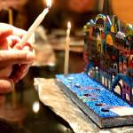 A father helps his daughter light a candle on their menorah at the Briat Elohim Jewish Congregation Hanukkah party on Dec. 1, 2018, in Kenai, Alaska. (Photo by Victoria Petersen/Peninsula Clarion)