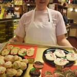 The Moose is Loose employee Elainnah Lagoutaris displays a pan of holiday-themed cookies Tuesday afternoon at the popular bakery in Soldotna. (Photo by Joey Klecka/Peninsula Clarion)