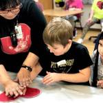 Residents from Heritage Place help kindergartner students make Dignity Mission T-shirts during a visit on Friday, Dec. 7, 2018, in Soldotna, Alaska. (Photo by Victoria Petersen/Peninsula Clarion)