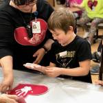 Residents from Heritage Place help kindergartner students make Dignity Mission T-shirts during a visit on Friday, Dec. 7, 2018, in Soldotna, Alaska. (Photo by Victoria Petersen/Peninsula Clarion)