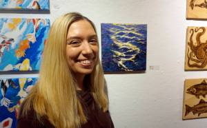 Maria Bernier stands by her painting, Chop, at the First Friday, Dec 7, 2018, opening of Bunnell Street Arts Centers 10x10 show in Homer, Alaska. (Photo by Michael Armstrong/Homer News)