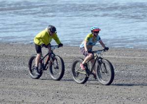 Catriona Reynolds finishes off a victory in the 10-mile bike at the Mouth to Mouth Wild Run and Ride on Monday, May 28, 2018, at the Kenai beach. On Reynolds tail is Sky Carver. (Photo by Jeff Helminiak/Peninsula Clarion)