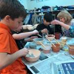 President of the Kenai Potters Guild and former Soldotna Elementary School librarian, Debbie Adamson, helps fifth-graders at Soldotna Elementary make ceramic bowls for a fundraiser that will buy buy new playground equipment for the school on Thursday, in Soldotna. (Photo by Victoria Petersen/Peninsula Clarion)