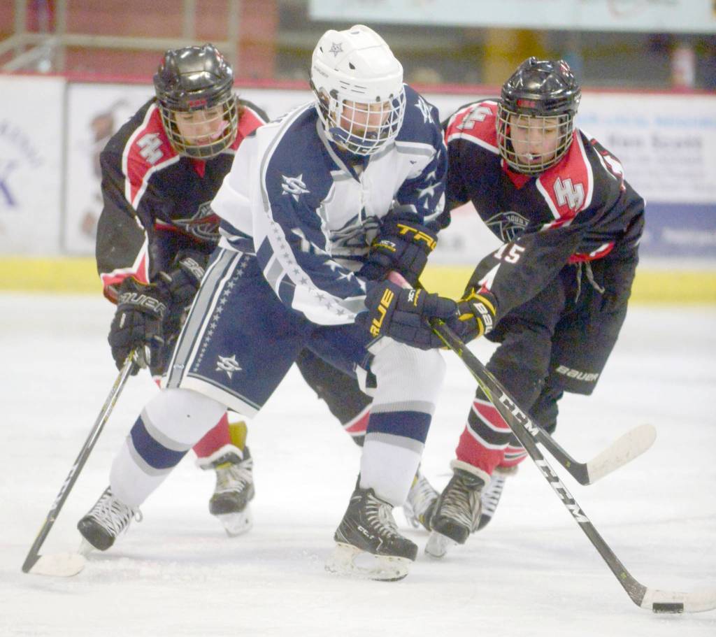 Soldotnas Dylan Walton battles for the puck with Houstons Isaiah Rasnake-Squires and Eric Preboski on Friday, Jan. 25, 2019, at the Soldotna Regional Sports Complex. (Photo by Jeff Helminiak/Peninsula Clarion)