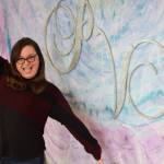 Local business owner Kylee Swircenski poses in front of the logo of her store, Positive Vibe, on Wednesday, Jan. 30, 2019 in Kenai. (Photo by Brian Mazurek/Peninsula Clarion)