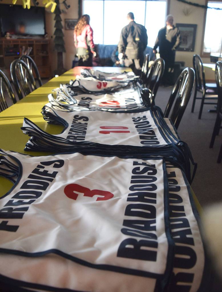 Piles of racing bibs wait to be claimed by contestants Saturday afternoon at the snowmachine drag races at Freddies Roadhouse near Ninilchik. (Photo by Joey Klecka/Peninsula Clarion)