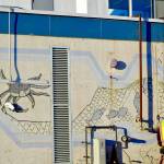 After construction workers removed siding from the facade of the Kenai Municipal Airport, a mural with iconic Kenai images like fishing nets, the St. Nicholas Russian Orthodox chapel and a dog musher, was revealed on Tuesday, Jan. 15, 2019 in Kenai, Alaska. (Photo by Victoria Petersen/Peninsula Clarion)