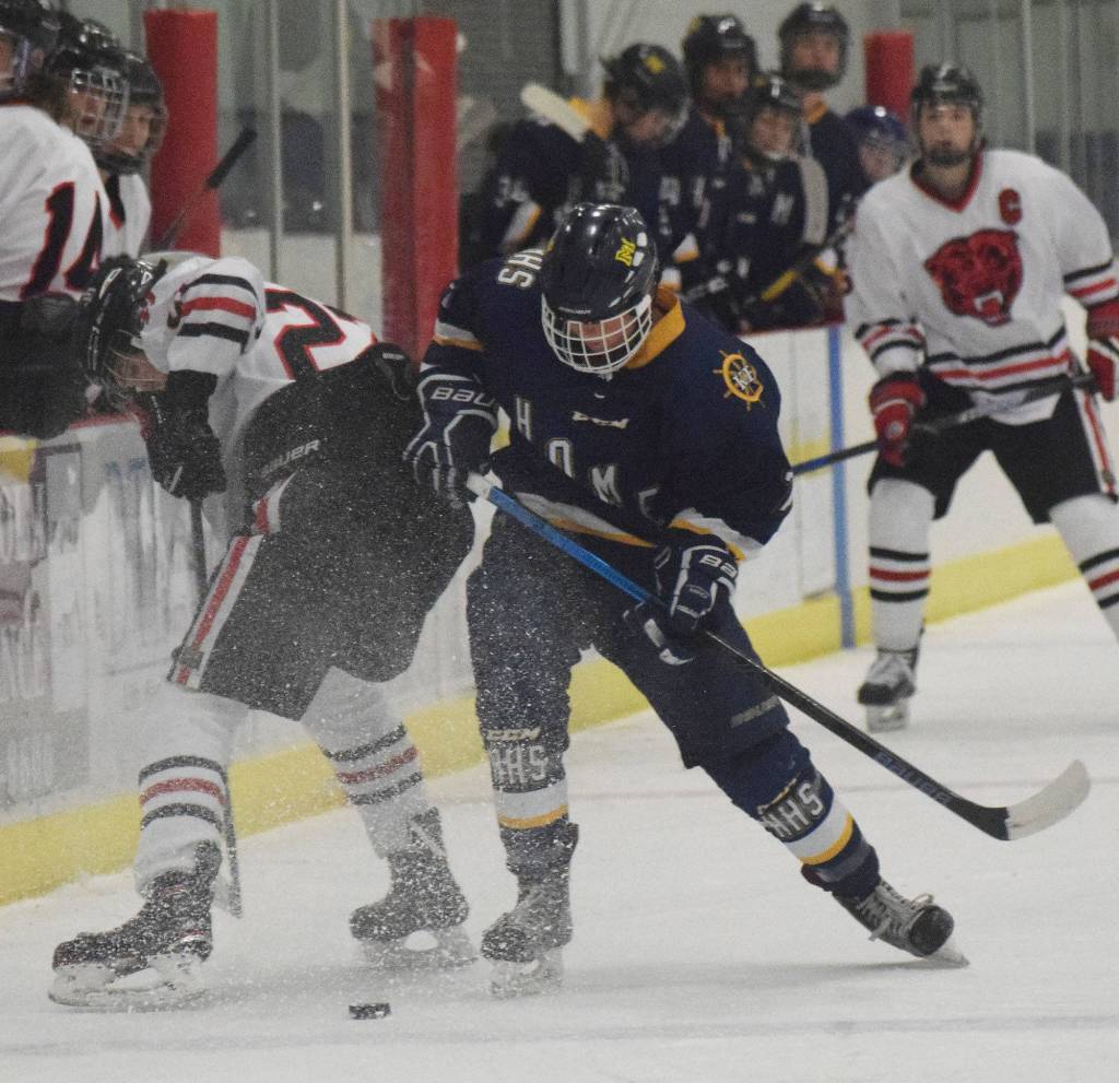 Homers Tyler Gilliland (right) battles for the puck with Juneaus Tyler Weldon Friday in a Div. II state semifinal at the Curtis Menard Sports Complex in Wasilla. (Photo by Joey Klecka/Peninsula Clarion)