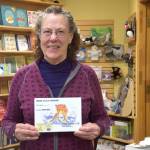 Local author Ann Mercer poses with her book, Miss Lucy Moose Falls Down in the Swamp at River City Books in Soldotna on Wednesday. (Photo by Brian Mazurek/Peninsula Clarion)