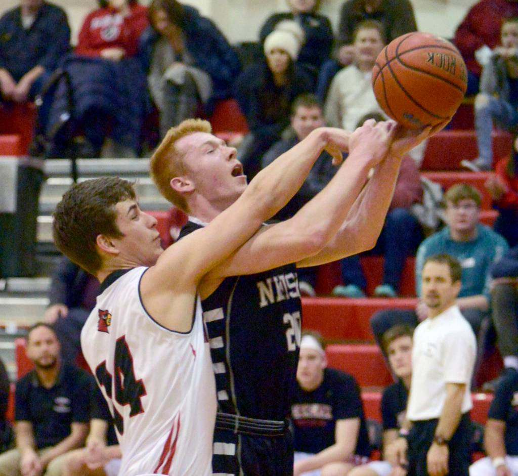 Kenai Centrals Logan Baker fouls Nikiskis Jace Kornstad on Tuesday, Feb. 19, 2019, at Kenai Central High School. (Photo by Jeff Helminiak/Peninsula Clarion)