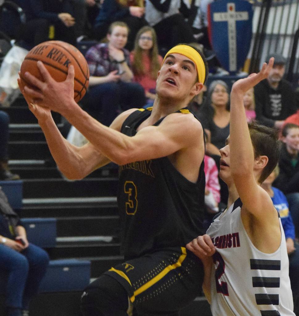Ninilchiks Garrett Koch (left) drives to the rim against Lumen Christi defender Brendon Gregory Saturday in the boys Peninsula Conference second-place contest. (Photo by Joey Klecka/Peninsula Clarion)