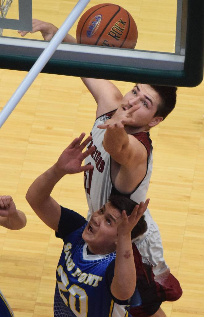 Nikolaevsks Michael Trail (top) leaps up for a rebound above Sand Points Steven Galovin Wednesday at the Class 1A boys state basketball championships at the Alaska Airlines Center in Anchorage. (Photo by Joey Klecka/Peninsula Clarion)