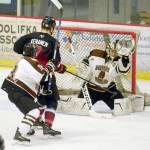 The puck squirts by the glove of Kenai River Brown Bears goaltender Gavin Enright, then goes over the goal, Thursday, March 14, night against the Minnesota Magicians at the Soldotna Regional Sports Complex. (Photo by Jeff Helminiak/Peninsula Clarion)