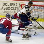 Kenai River Brown Bears forward Zach Krajnik slips the puck through the legs of Fairbanks Ice Dogs goalie Nate Reid in front of Ice Dogs defenseman John Stampohar on Friday, March 22, 2019, at the Soldotna Regional Sports Complex. The short-handed goal was the game-winner. (Photo by Jeff Helminiak/Peninsula Clarion)