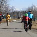 This April 3, 2019, photo shows people running and biking at Westchester Lagoon in Anchorage, Alaska, with the snow-covered Chugach Mountains in the distance. Much of Anchorages snow disappeared as Alaska experienced unseasonably warm weather in March. (AP Photo/Mark Thiessen)