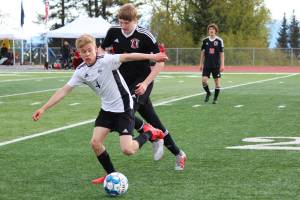 Nikiskis Gavin White tries to keep control of the ball under pressure from Kenais Evan Stockton during a Peninsula Conference Soccer Tournament game Friday, May 17, 2019 at Homer High School in Homer, Alaska. Kenai advanced to the conference championship game on Saturday with a 3-0 win over the Bulldogs. (Photo by Megan Pacer/Homer News)