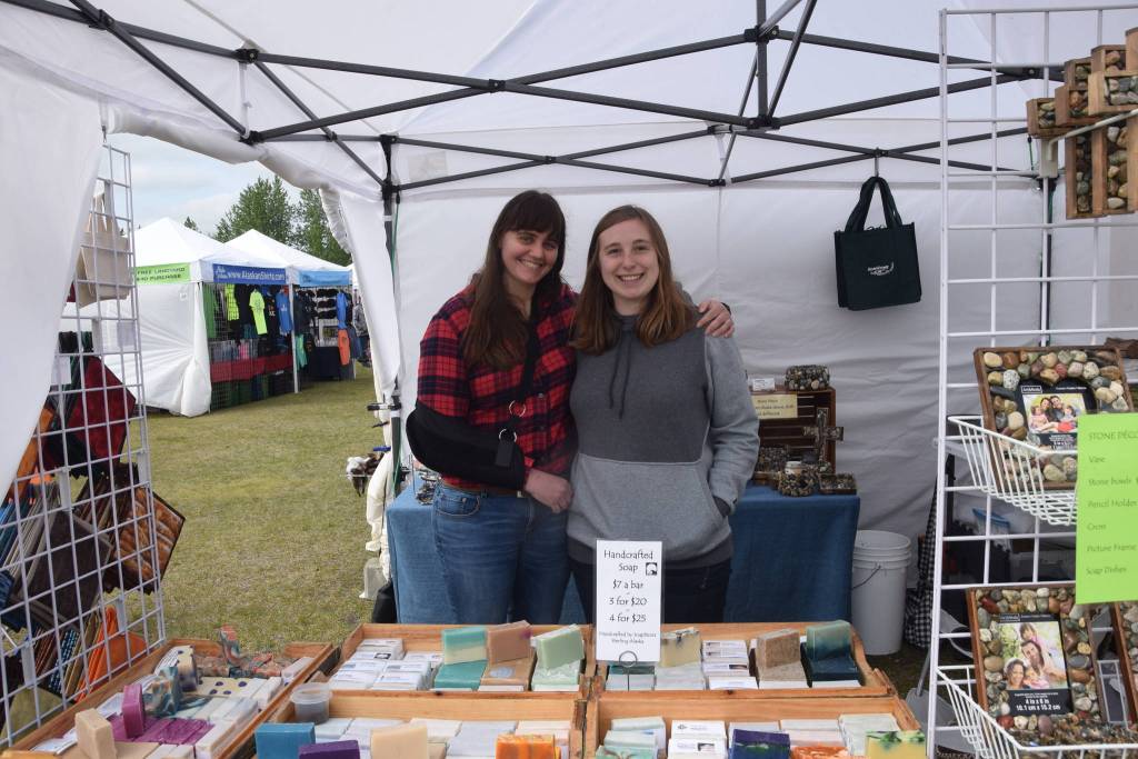 Audra Johnson, left, and Ayanna Carter, right, pose in front of handmade soaps crafted by Carters grandparents during the Kenai River Festival at Soldotna Creek Park in Soldotna, Alaska on June 8, 2019. (Photo by Brian Mazurek/Peninsula Clarion)