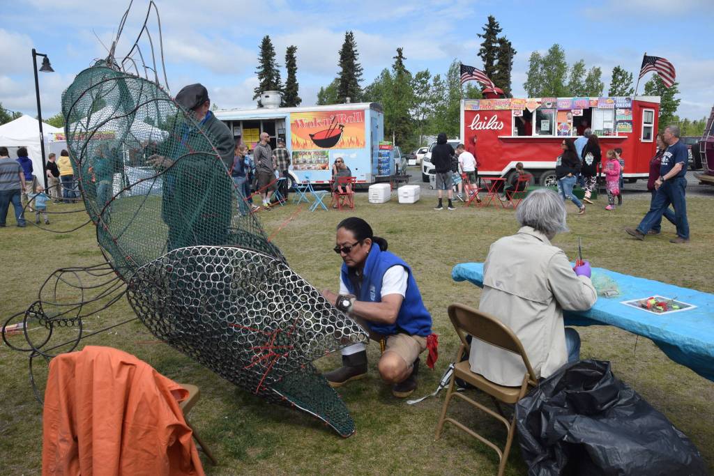 KPC Fine Arts Professor Cam Choy works on a salmon sculpture as a collaboration with the Kenai Watershed Forum during the Kenai River Festival at Soldotna Creek Park in Soldotna, Alaska on June 8, 2019. (Photo by Brian Mazurek/Peninsula Clarion)