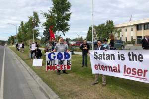 Demonstrators hold signs outside the Kenai Peninsula Borough building in protest of an invocation by a member of the Satanic Temple on Tuesday, June 18, 2019 in Soldotna, Alaska. The invocation was the first given by the Satanic Temple since the borough changed its invocation policy following an Alaska Superior Court decision finding the policy unconstitutional and in violation of the states constitutions establishment clause. (Photo courtesy Aud Walaszek)