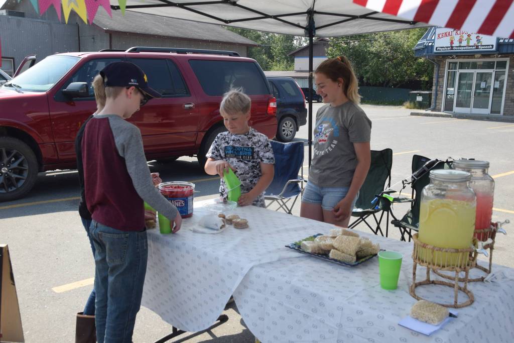 Nathan and Avery Powell, right, serve customers at their lemonade stand in outside of Kenai Kids Therapy during Lemonade Day in Soldotna, Alaska on June 29, 2019. (Photo by Brian Mazurek/Peninsula Clarion)