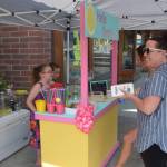 Kinley Clack, left, and Brooklynne Timm serve some customers at their lemonade stand outside of Sweeneys during Lemonade Day in Soldotna, Alaska on June 29, 2019. (Photo by Brian Mazurek/Peninsula Clarion)