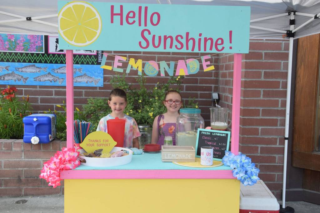 Brooklynne Timm, left, and Kinley Clack, right, smile for the camera at their lemonade stand outside of Sweeneys during Lemonade Day in Soldotna, Alaska on June 29, 2019. (Photo by Brian Mazurek/Peninsula Clarion)