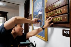 Michael Penn | Juneau Empire                                Ron Lumba, of the Alaska State Capitols maintenance staff, adds the Majority Leader plate to the front of the office of Sen. Lyman Hoffman, D-Bethel, on the first day of the Second Special Session of the Alaska Legislature in Juneau on Monday.