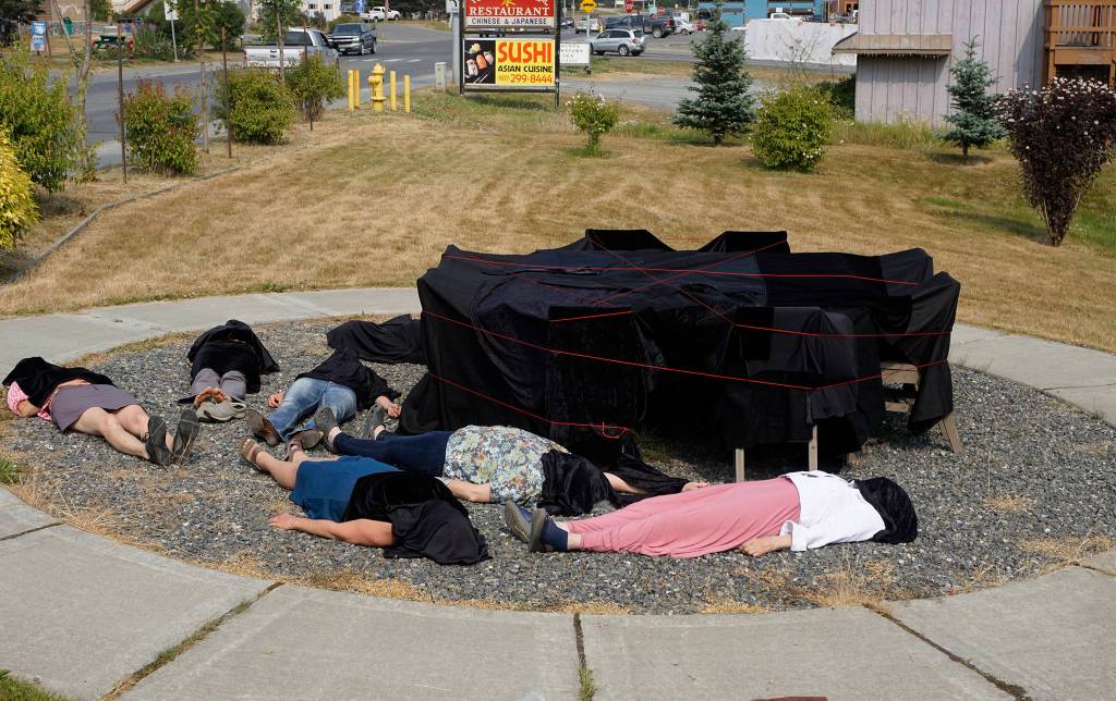 People draped in black lie down on July 9, 2019, by Sean Derrys public art sculpture in Homer, Alaska, as part of a statewide art intervention to protest Gov. Mike Dunleavys veto of a $700,000 state appropriation to the Alaska State Council on the Arts. They also supported a general override of Dunleavys vetoes that will affect funding for the University of Alaska, public radio and other programs. Derrys sculpture was commissioned as a 1% for art project associated with the remodeling of Pioneer Hall at the Kachemak Bay Campus, Kenai Peninsula College, University of Alaska. The protest was not sanctioned by the college. (Photo by Michael Armstrong/Homer News)