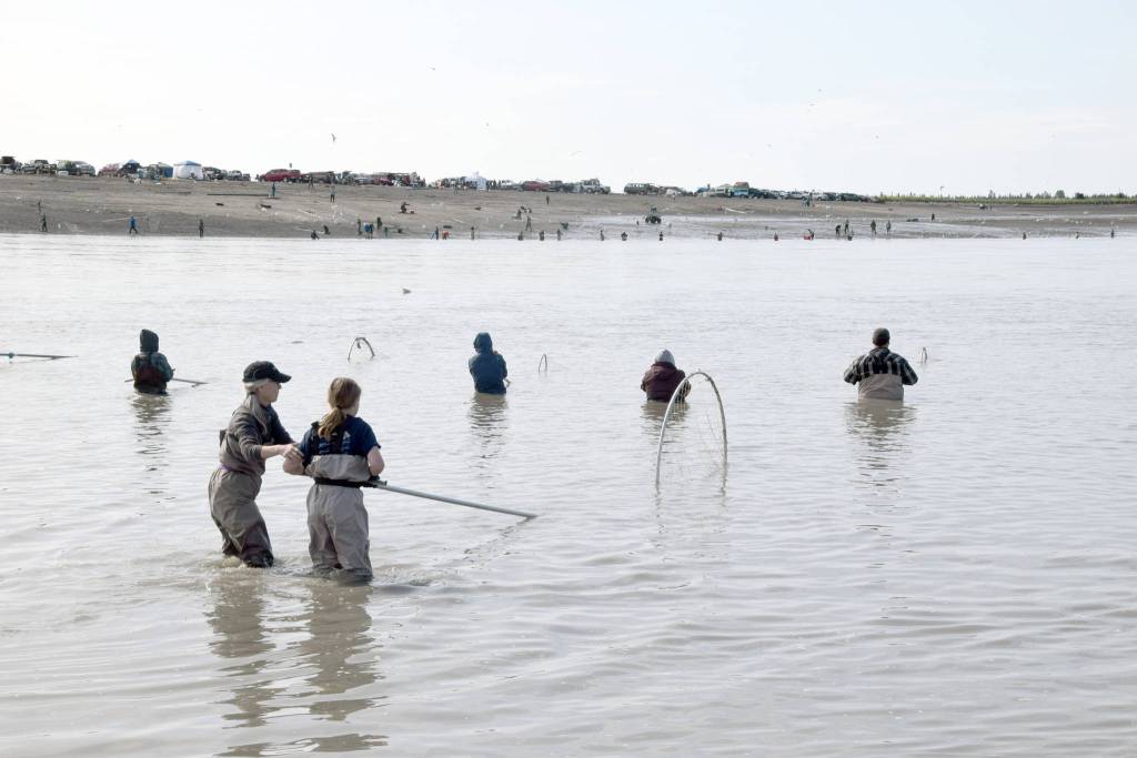 Claudia Henley, front left, shows her grandson Austin Feagin a few tips while dipnetting on the North Kenai Beach on Wednesday, July 17, 2019. (Photo by Brian Mazurek/Peninsula Clarion)