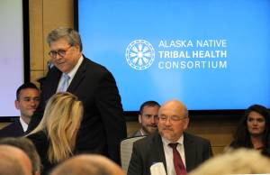 In this May 29, 2019 file photo U.S. Attorney General William Barr, standing, greets participants at a roundtable discussion at the Alaska Native Tribal Health Consortium in Anchorage, Alaska. Alaska Native villages are receiving almost $5 million from the U.S. Justice Department to combat numerous public safety problems, including no law enforcement presence in some communities. The announcement Tuesday, July 30, 2019, comes nearly two months after Barr met with tribal representatives during a visit to the state who detailed slow response times from authorities, violence against women and abuse of alcohol and drugs, including opioids. (AP Photo/Mark Thiessen, File)