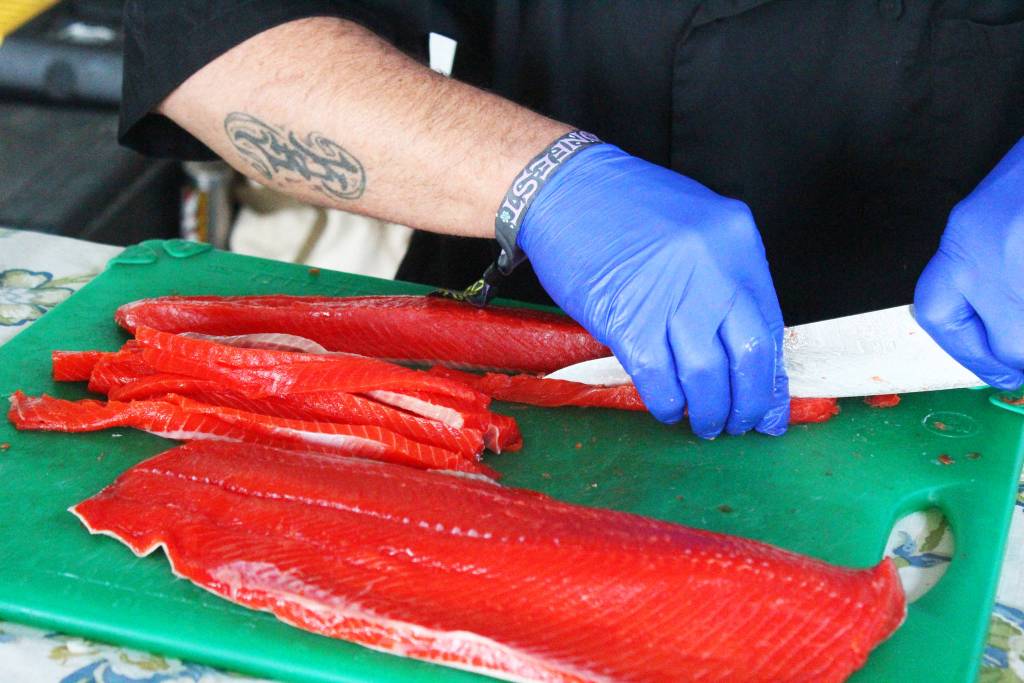 Evan Vogl, chef at the Little Mermaid in Homer, prepares salmon for a poke during a food demonstration on Friday, Aug. 2, 2019 at Salmonfest in Ninilchik, Alaska. The chef at the festival food demos are a take on the chef at the market that happens at the Homer Farmers Market. (Photo by Megan Pacer/Homer News)
