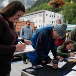 Michael Penn | Juneau Empire                                Monika Kunat (left) signs an application petition to recall Gov. Mike Dunleavy on Thursday with others at the Planet Alaska Gallery in Juneau.