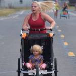A 5K runner pushing a stroller approaches the finish line Saturday, Aug. 10, 2019, at the 32nd annual Run for Women in Kenai, Alaska. (Photo by Joey Klecka/Peninsula Clarion)