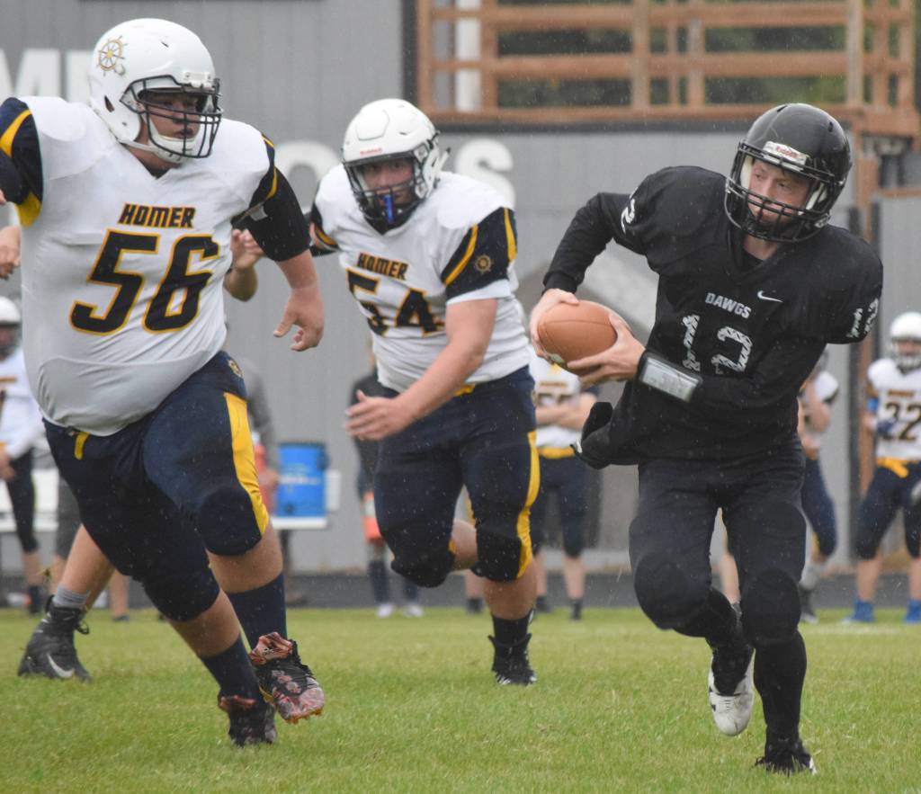 Nikiski quarterback Noah LItke scrambles away from Homers Zack Condon and Sean Pilant on Friday, Aug. 30, 2019, at Nikiski High School in Nikiski, Alaska. (Photo by Jeff Helminiak/Peninsula Clarion)