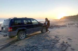 Kat Sorensen, the author, walks alongside her 1996 Jeep Grand Cherokee on Kenai Beach in May 2018. (Photo by Megan Pacer/Homer News)