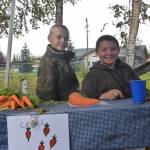 Tolson Hall, left, and Kirk Denbrock, right, show off the carrots they harvested at the Montessori Farmers Market at the Soldotna Montessori School on Sept. 13, 2019. (Photo by Brian Mazurek/Peninsula Clarion)