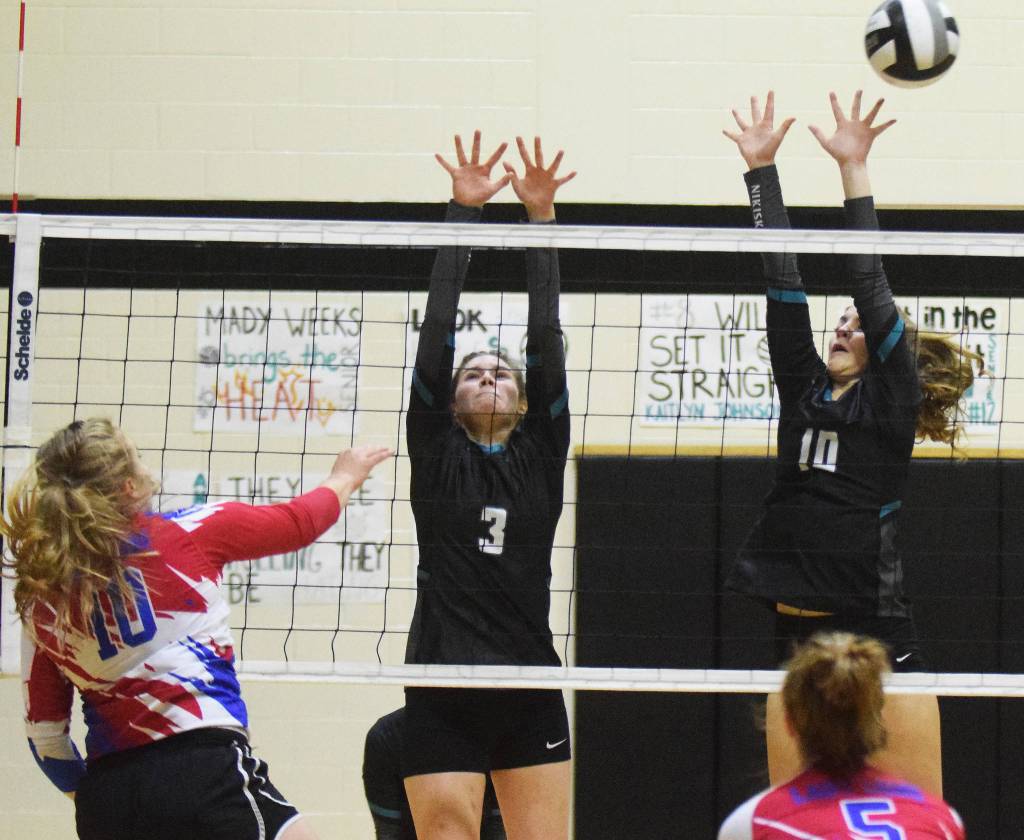 Nikiskis Jaycee Tauriainen (left) and Lillian Carstens team up for a block Friday, Sept. 27, 2019, against ACS at Nikiski High School. (Photo by Joey Klecka/Peninsula Clarion)
