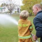 Brian Mazurek / Peninsula Clarion                                A young firefighter-in-training practices knocking down a water jug with a fire hose during the Central Emergency Services Open House at Fire Station 1 in Soldotna, Saturday.