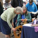 Alrene Haines, left instructs Donna Jones, right on how to use a spinning wheel during the Fireweed FiberFest at the Soldotna Regional Sports Complex on Sept. 28, 2019. (Photo by Brian Mazurek/Peninsula Clarion)